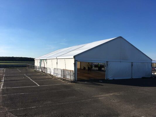Long-term marquee hire for events with metal railing outside on concrete car park